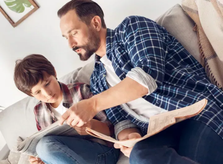 dad and child discuss something from the newspaper