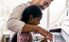 Dad teaches child to play piano