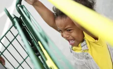 little girl having tantrum while holding on to shopping trolley