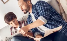 dad and child discuss something from the newspaper