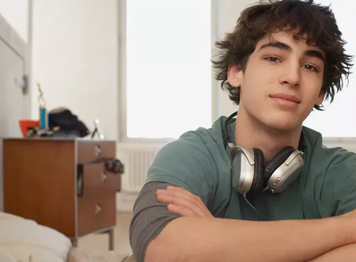 teenage boy in his bedroom looks at camera