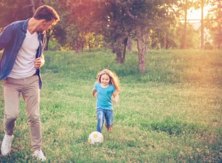 dad playing backyard soccer with daughter